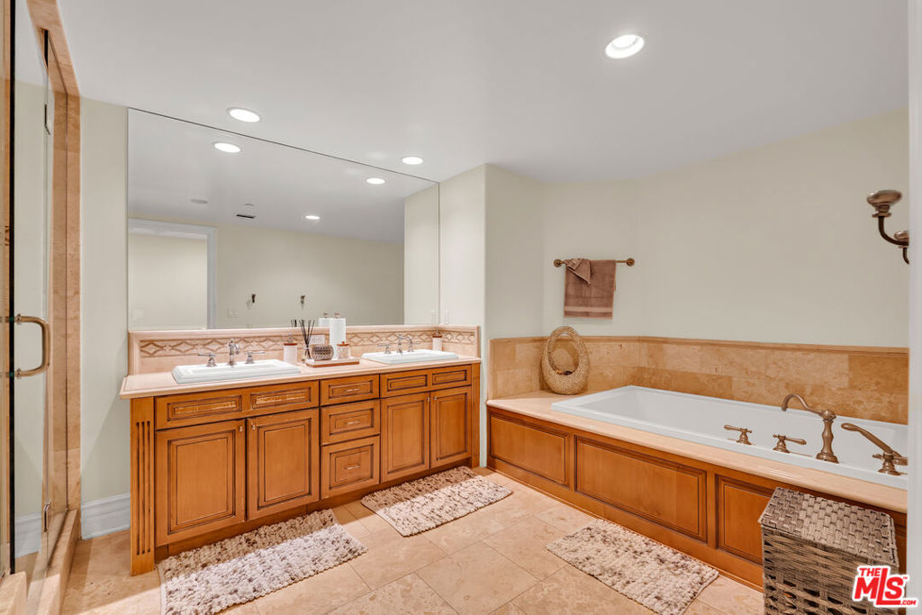 Bathroom with a double-sink wood vanity, large mirror, and built-in soaking tub.
