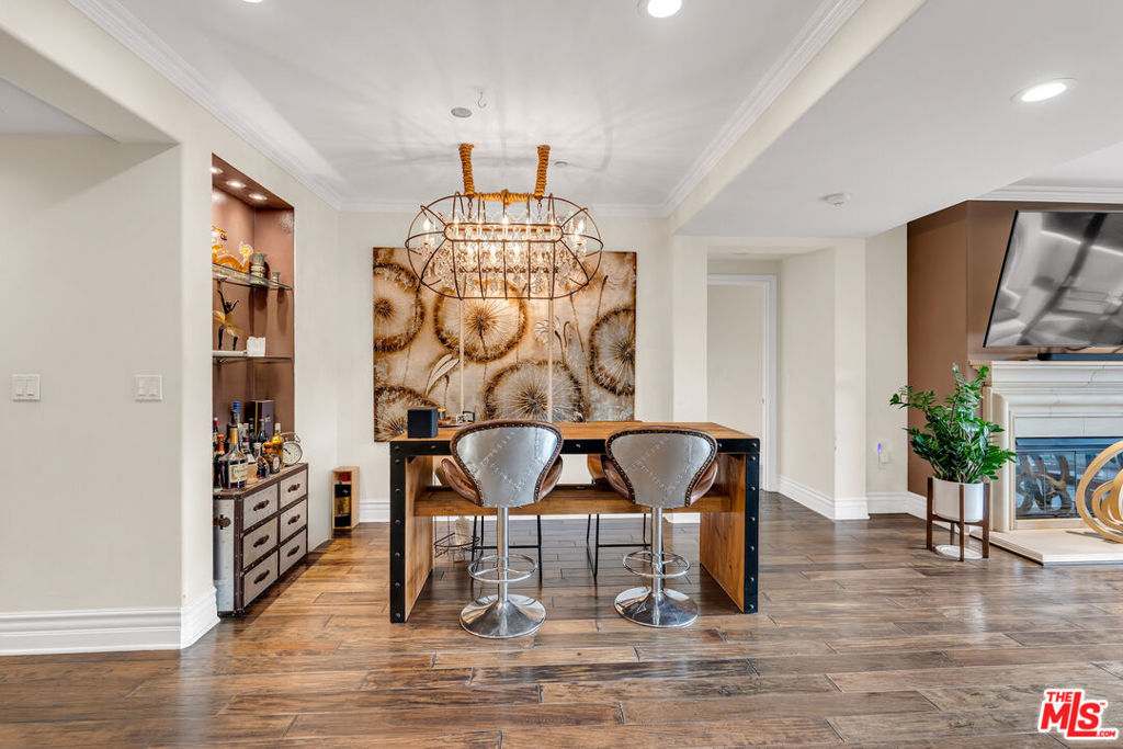 Dining area with a bar-height table, two upholstered stools, and a chandelier.