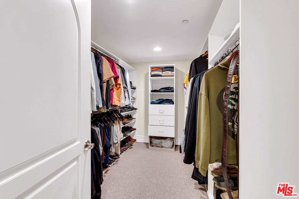 Walk-in closet with clothing racks on both sides and built-in drawers at the far end.