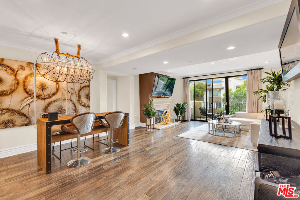 Open-plan living and dining room with wood floors, a fireplace, and sliding doors to a balcony.