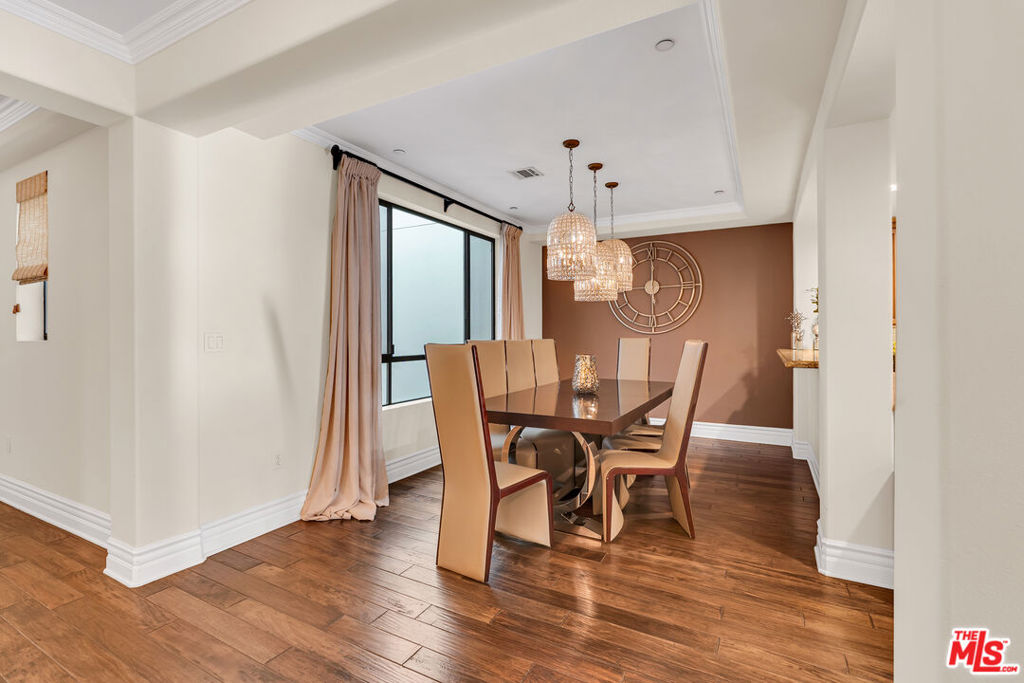 Dining room with a dark wood table, tan chairs, woven pendant lights, and hardwood floors.