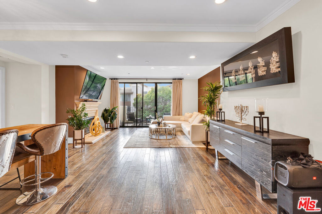 Living room with a fireplace, dark wood floors, and sliding glass doors to a balcony.