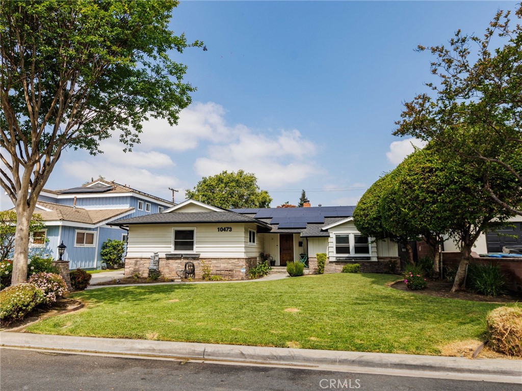 Single-story home with rooftop solar panels, stone veneer, and a broad front lawn.