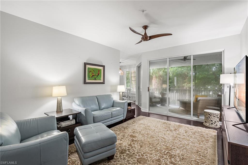 Living room with pale blue leather seating, patterned rug, and sliding doors to a leafy lanai.