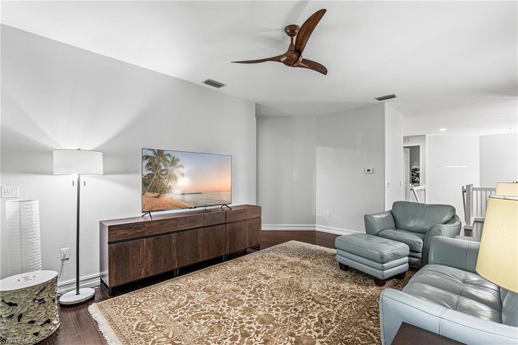 Living room with gray leather seating, a patterned rug, and a dark wood media console.