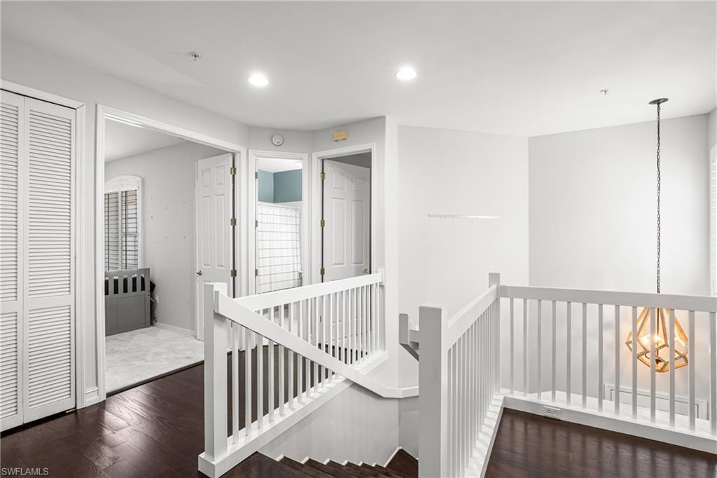 Interior staircase with white railings, dark wood flooring, and a geometric pendant light.