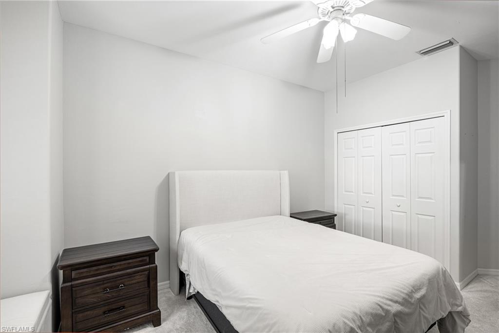 Bedroom with a white bed, dark wood nightstands, and sliding closet doors.