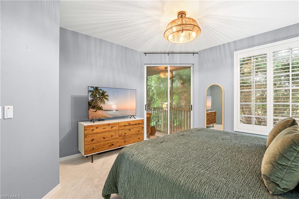 Bedroom with a green quilted bed, wood dresser and television, and sliding glass doors to a balcony.