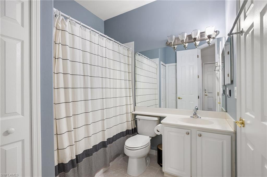 Bathroom with blue-gray walls, white vanity, and striped shower curtain.