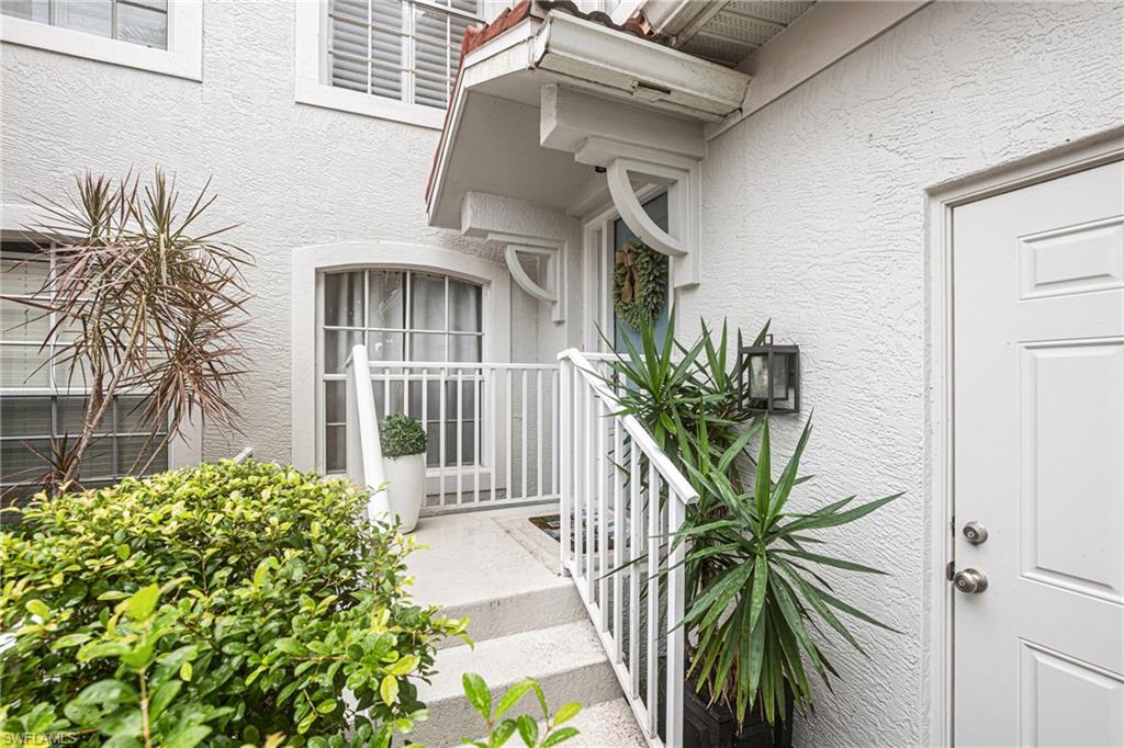 Residence entrance with white-railed steps, a white door, and tropical plants.
