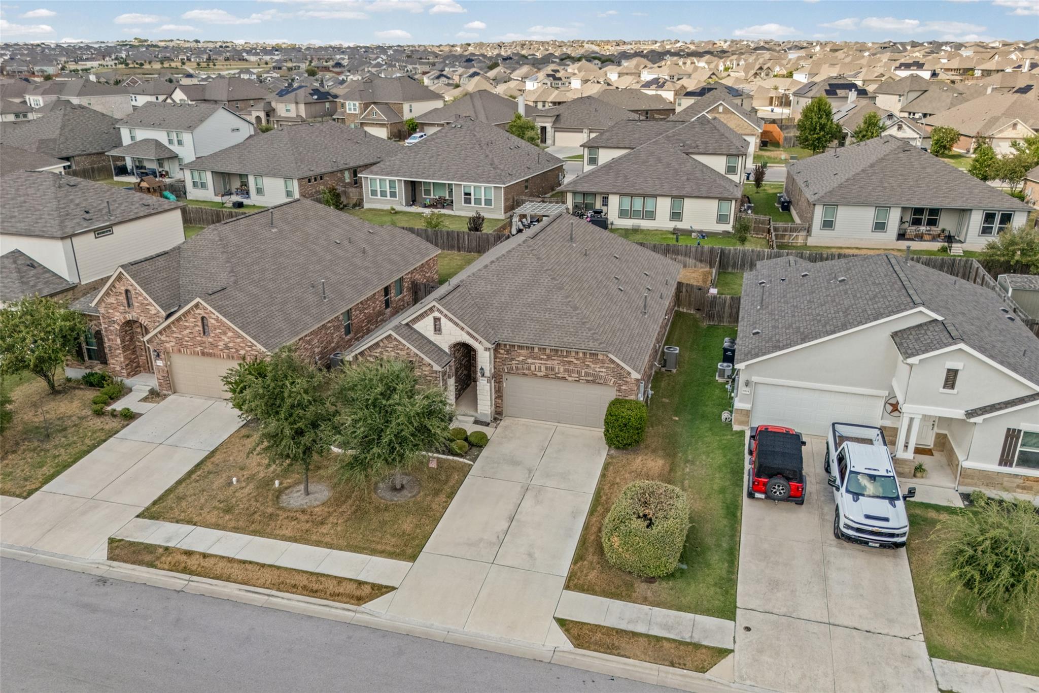 Aerial view of a suburban neighborhood with brick homes, fenced yards, and concrete driveways.