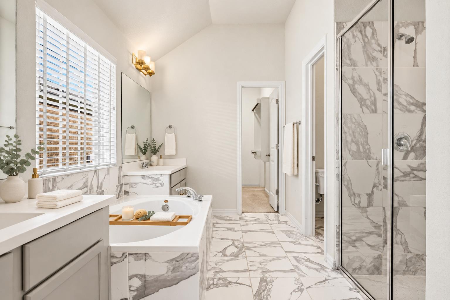 Bright bathroom with a soaking tub, marble-look tile, and glass-enclosed shower.