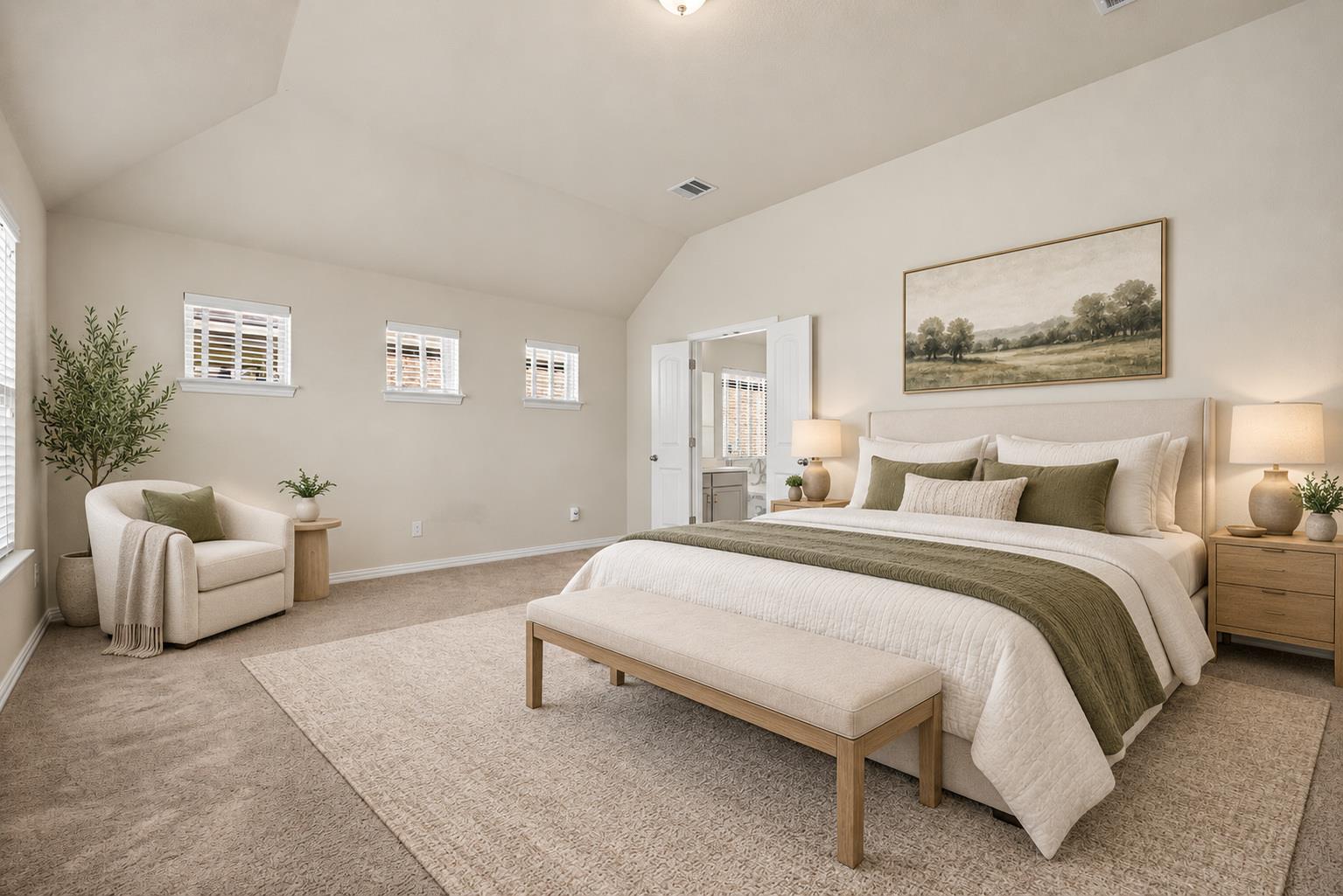 Staged bedroom with a white bed, olive-green accents, upholstered bench, and armchair beside windows.