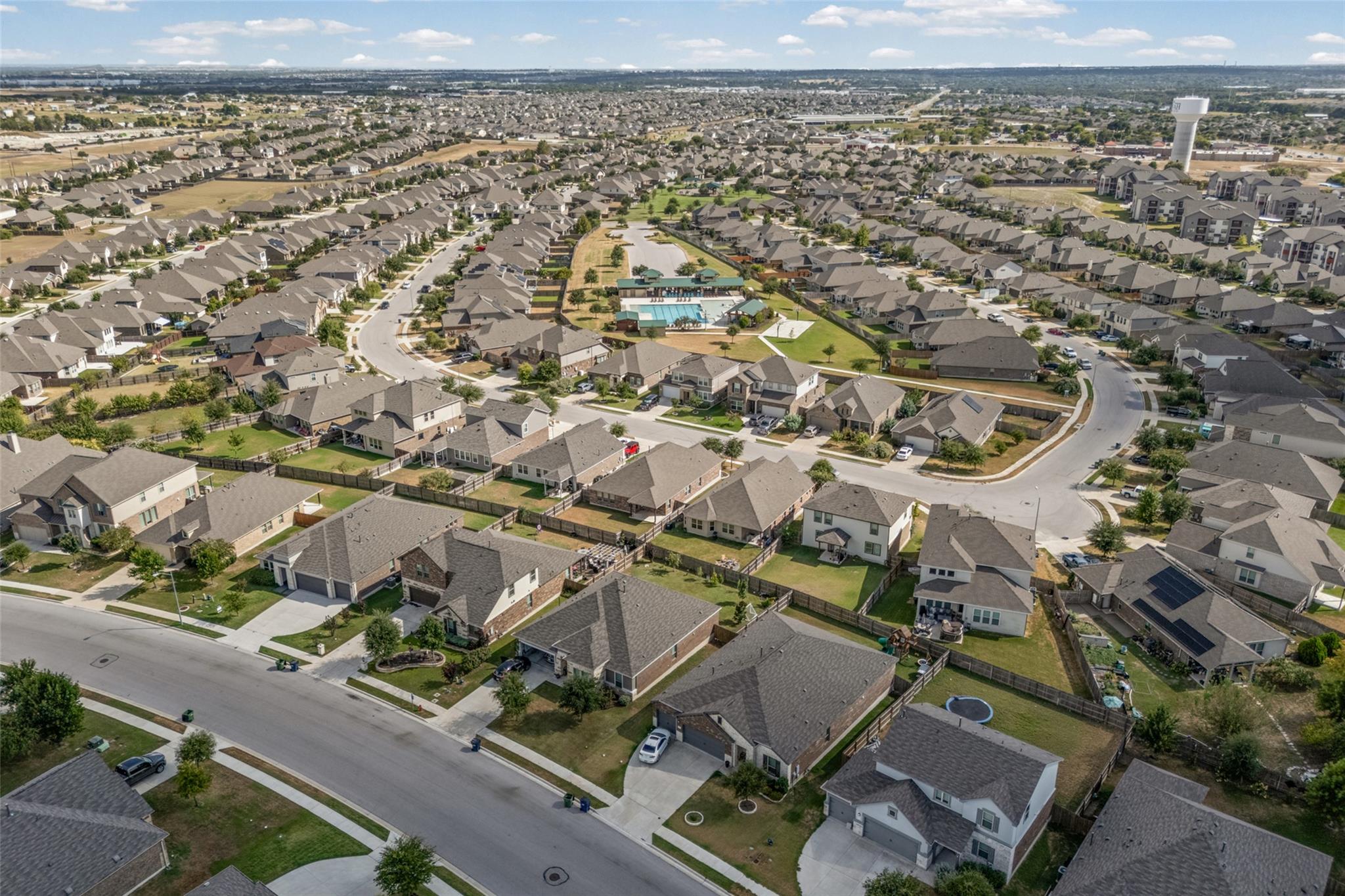 Aerial view of a suburban neighborhood with rows of homes and a central community pool.