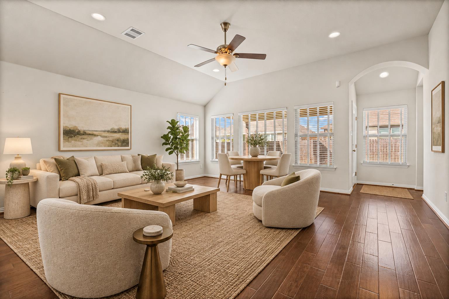 Living room with cream seating, vaulted ceiling, ceiling fan, and adjoining dining area.