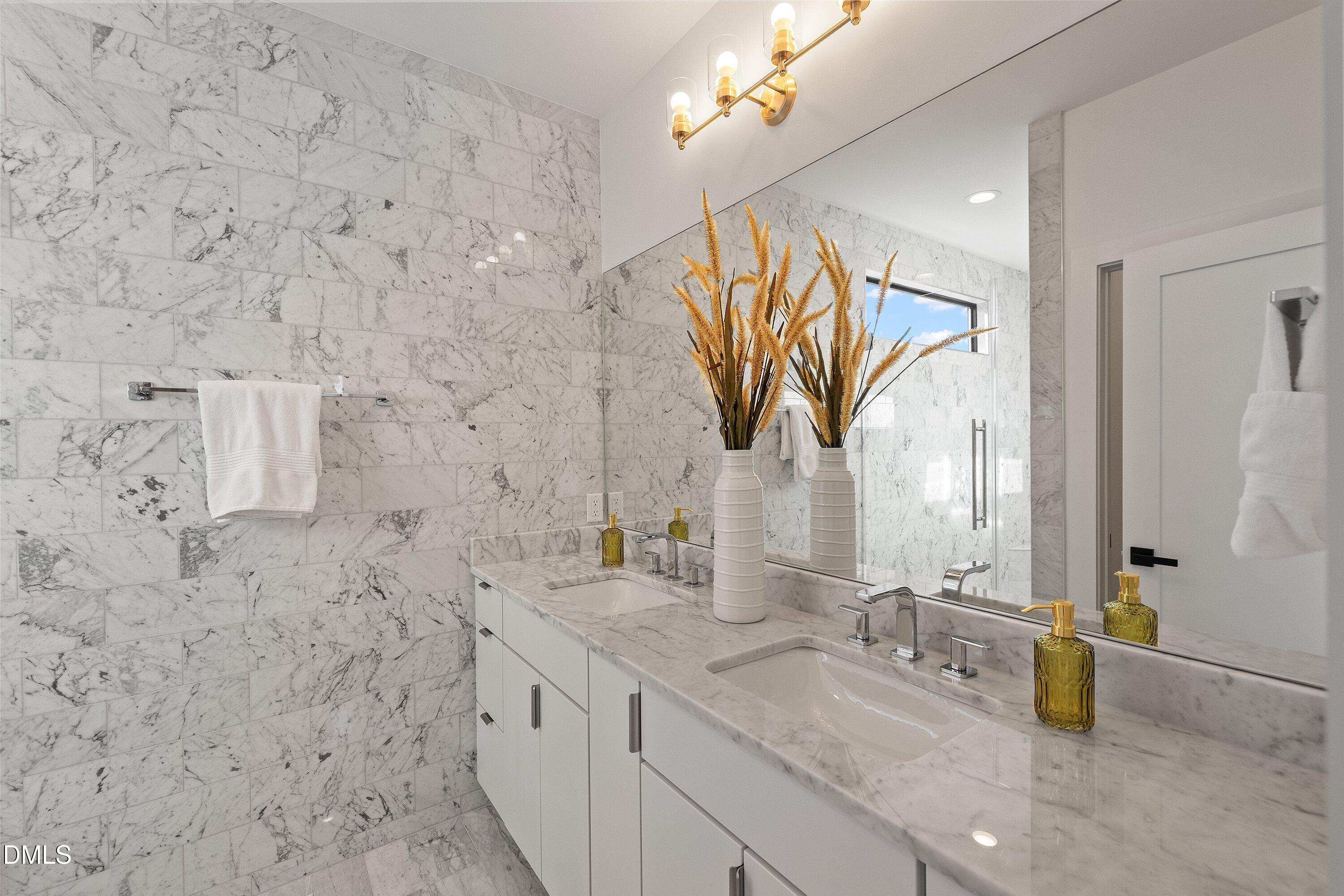Marble bathroom with a double-sink vanity, large mirror, and glass shower.