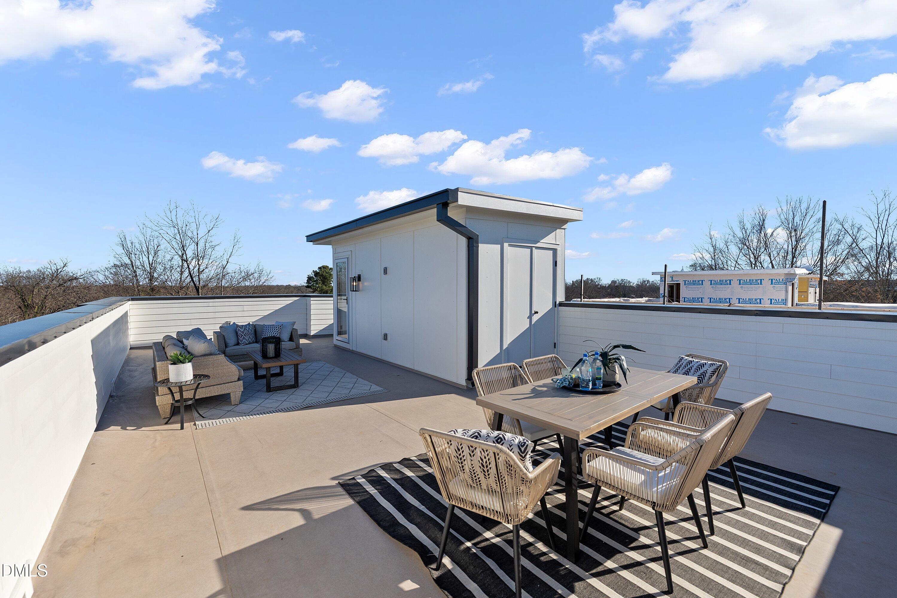 Rooftop terrace with dining and lounge seating beside a small rooftop structure.