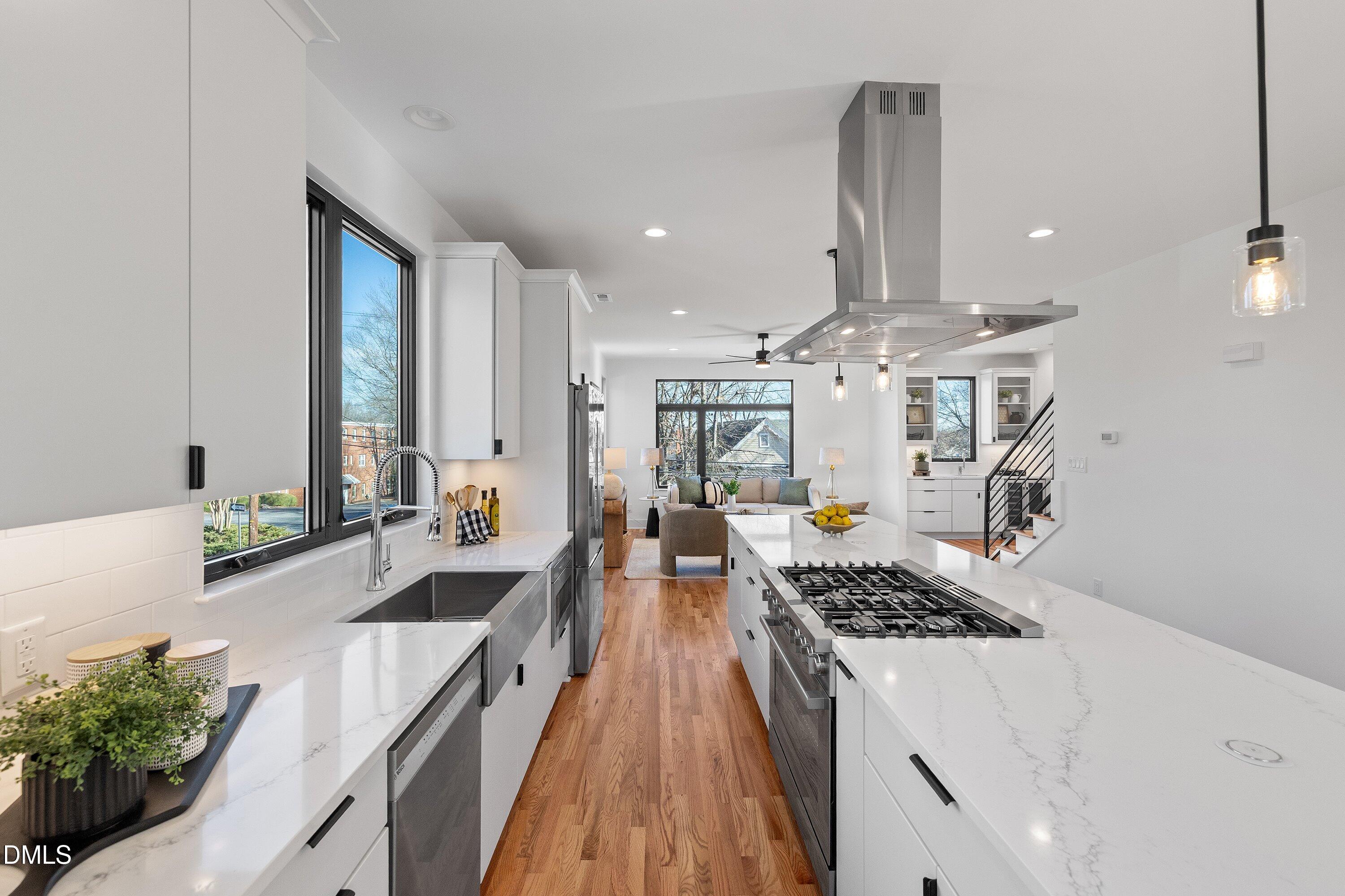 Open-plan kitchen with a marble island and gas cooktop, opening onto a bright living area.
