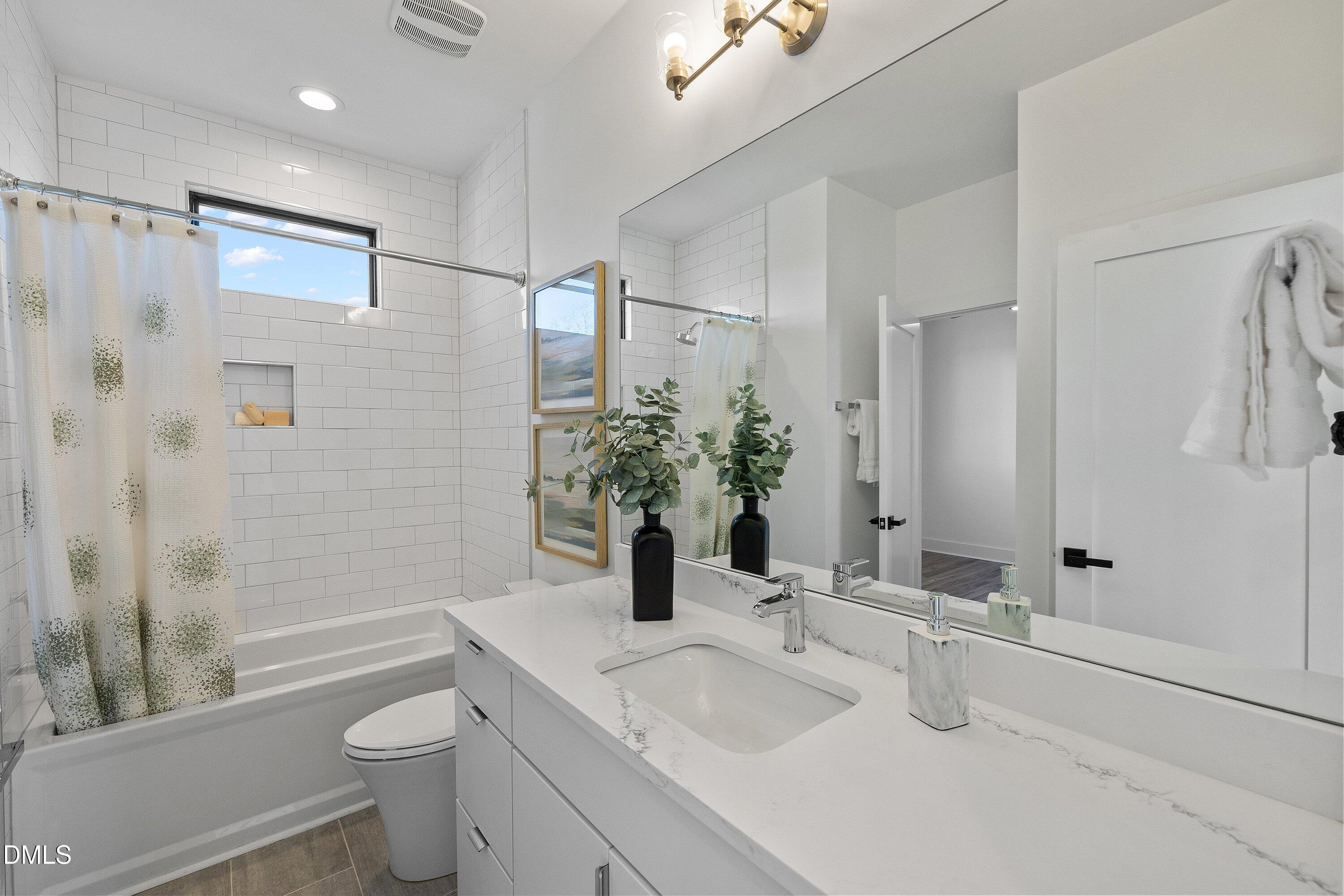 Bright bathroom with a subway-tile tub surround and a long marble-look vanity.