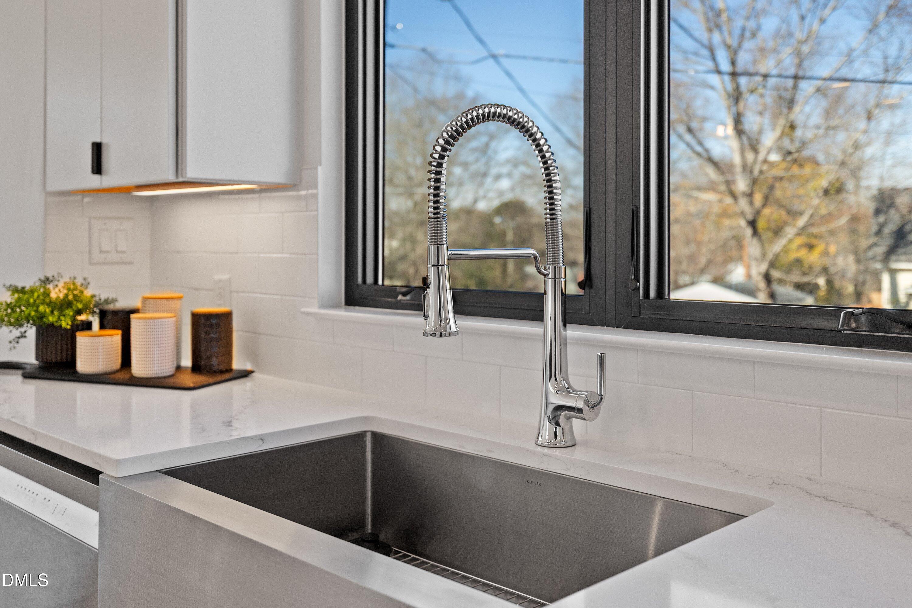 Modern kitchen sink with a spring-pull faucet beneath a wide black-framed window.