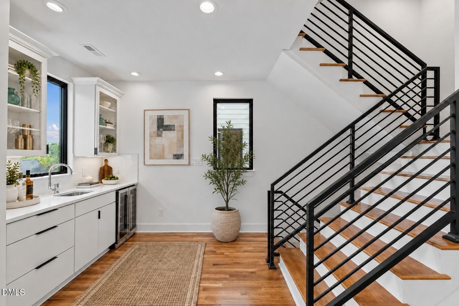 Kitchen beside a staircase with black metal railings and warm wood treads.