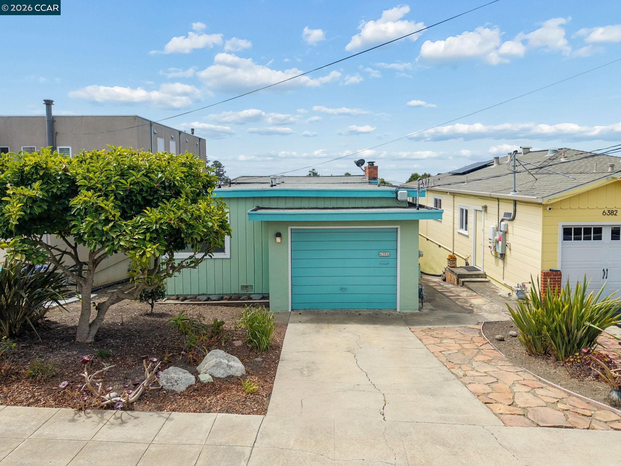 Turquoise home with matching garage door, concrete driveway, and landscaped front yard.