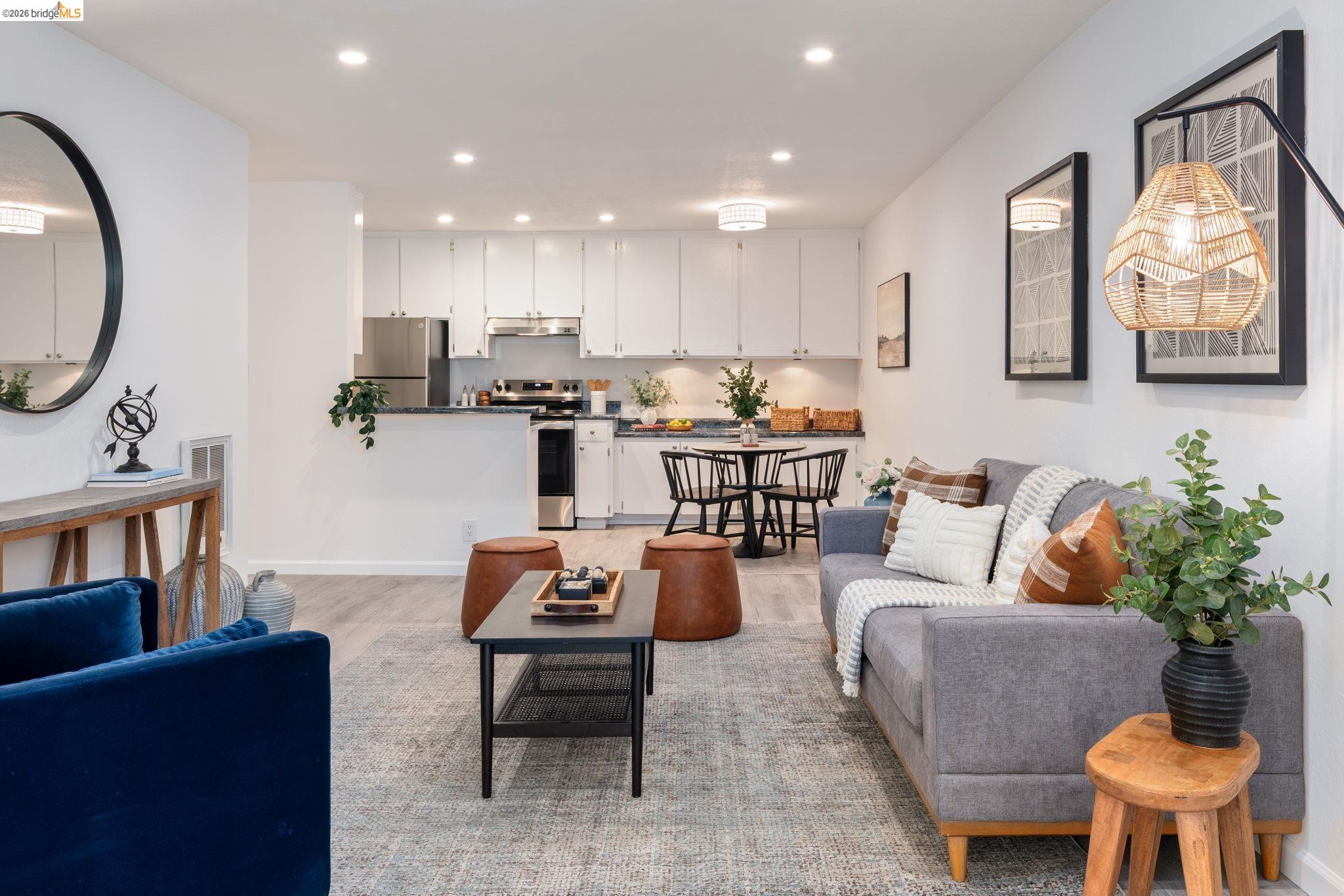 Open-plan living room and kitchen with white cabinetry, a gray sofa, and a blue armchair.