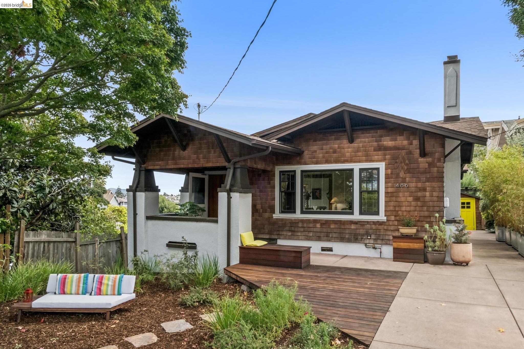 Home numbered 486 with brown shingle siding, a covered porch, and a wood deck.