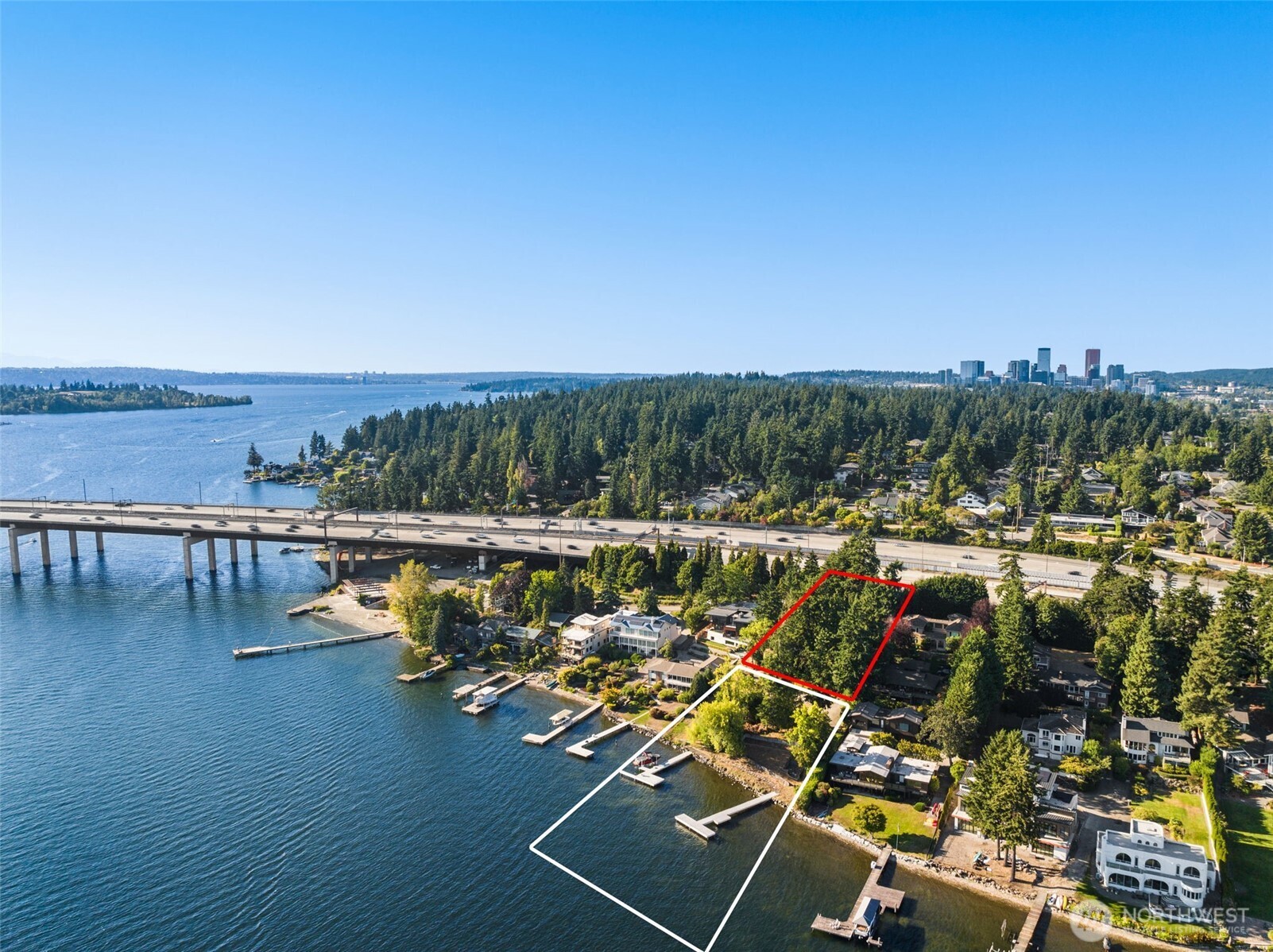 Aerial view of a Lake Washington waterfront lot with docks, a bridge, and Bellevue’s skyline.