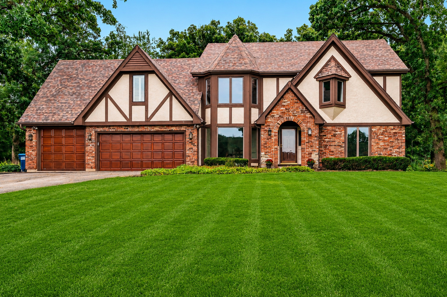 Tudor-style home with brick and stucco exterior, multiple gables, and a two-car garage.