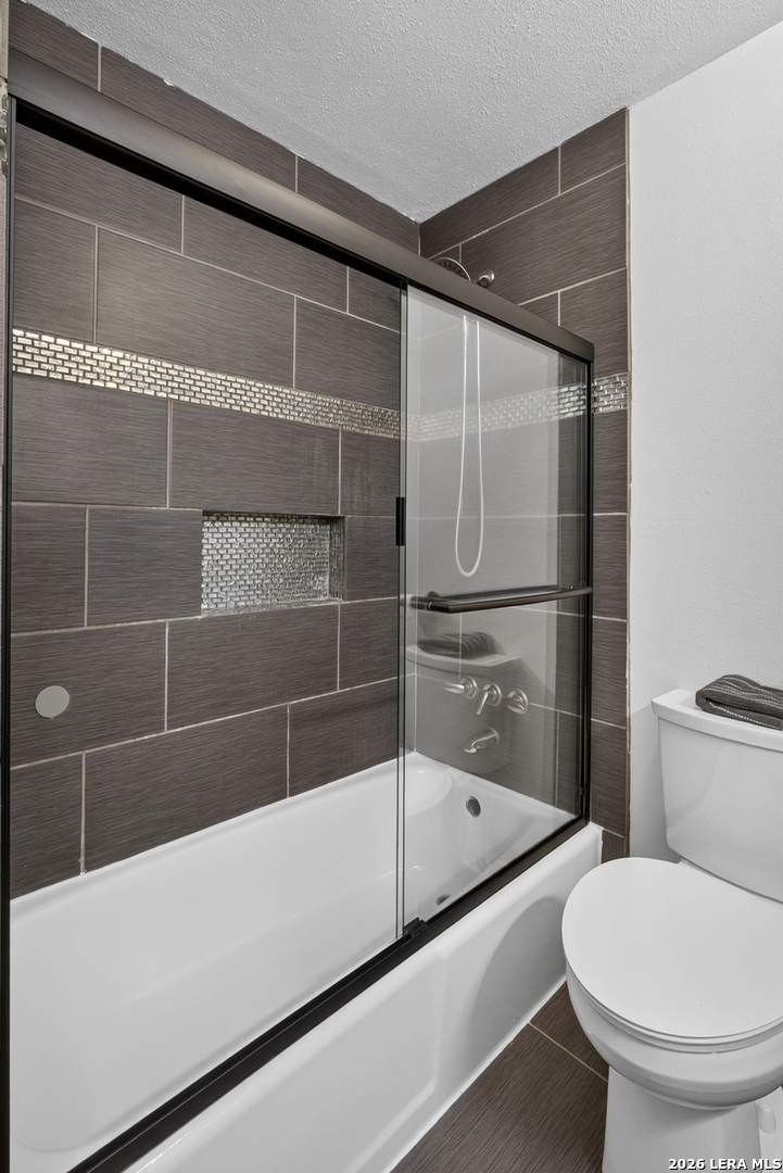 Bathroom with a dark tiled shower and glass enclosure beside a white bathtub and toilet.
