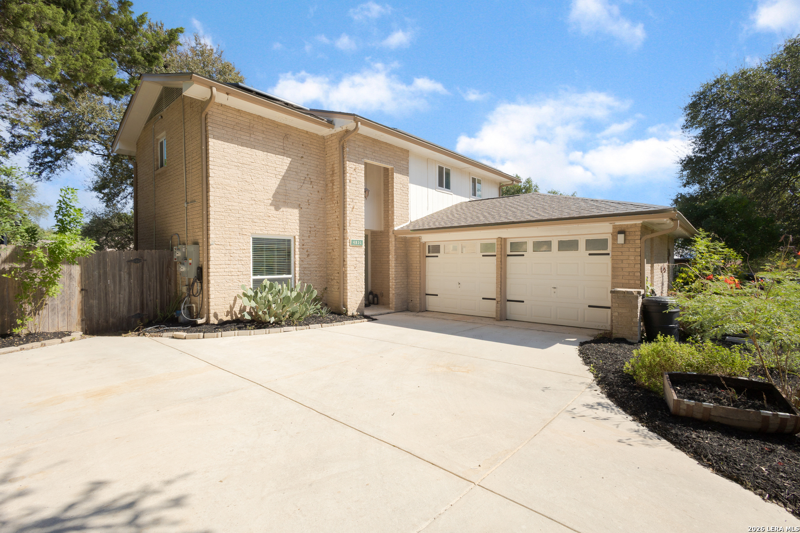 Two-story brick home with a broad concrete driveway and double garage.