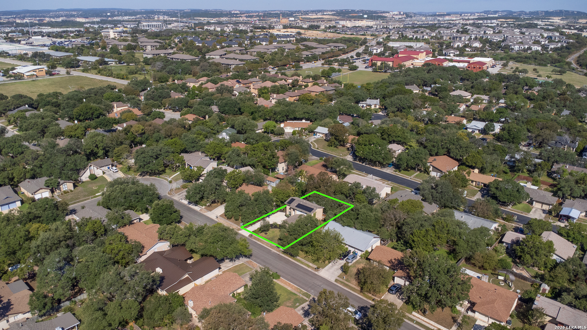 Aerial view of the outlined home and lot amid a tree-lined San Antonio neighborhood.