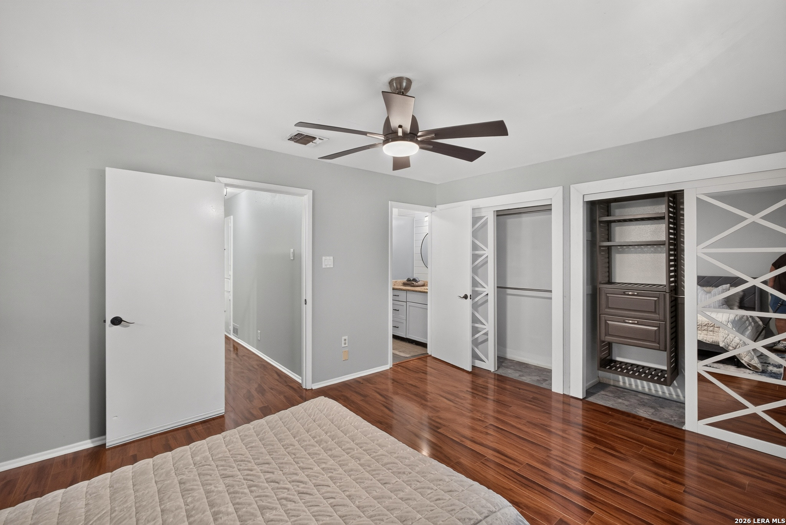 Bedroom with hardwood floors, a ceiling fan, and an open built-in closet.