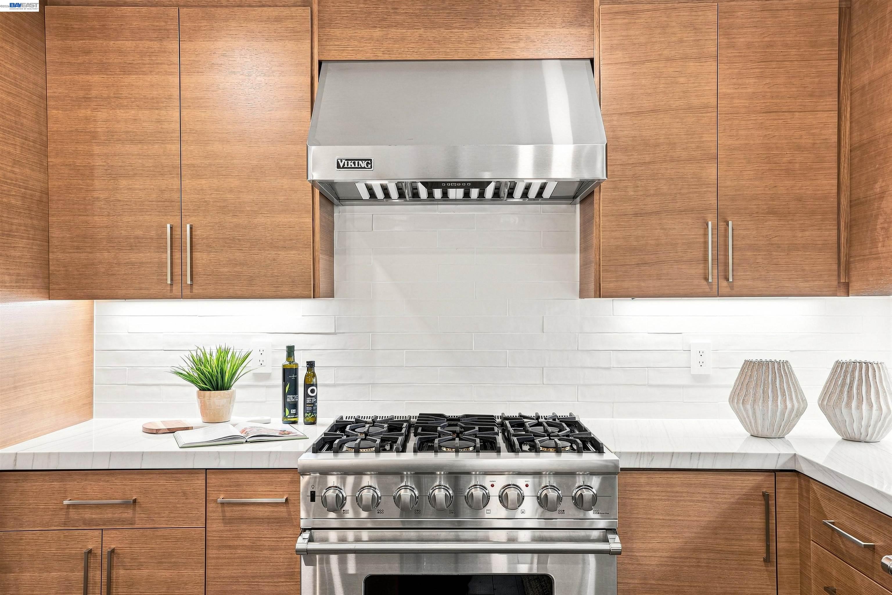 Kitchen with wood cabinets, white tile backsplash, and a stainless-steel Viking range and hood.