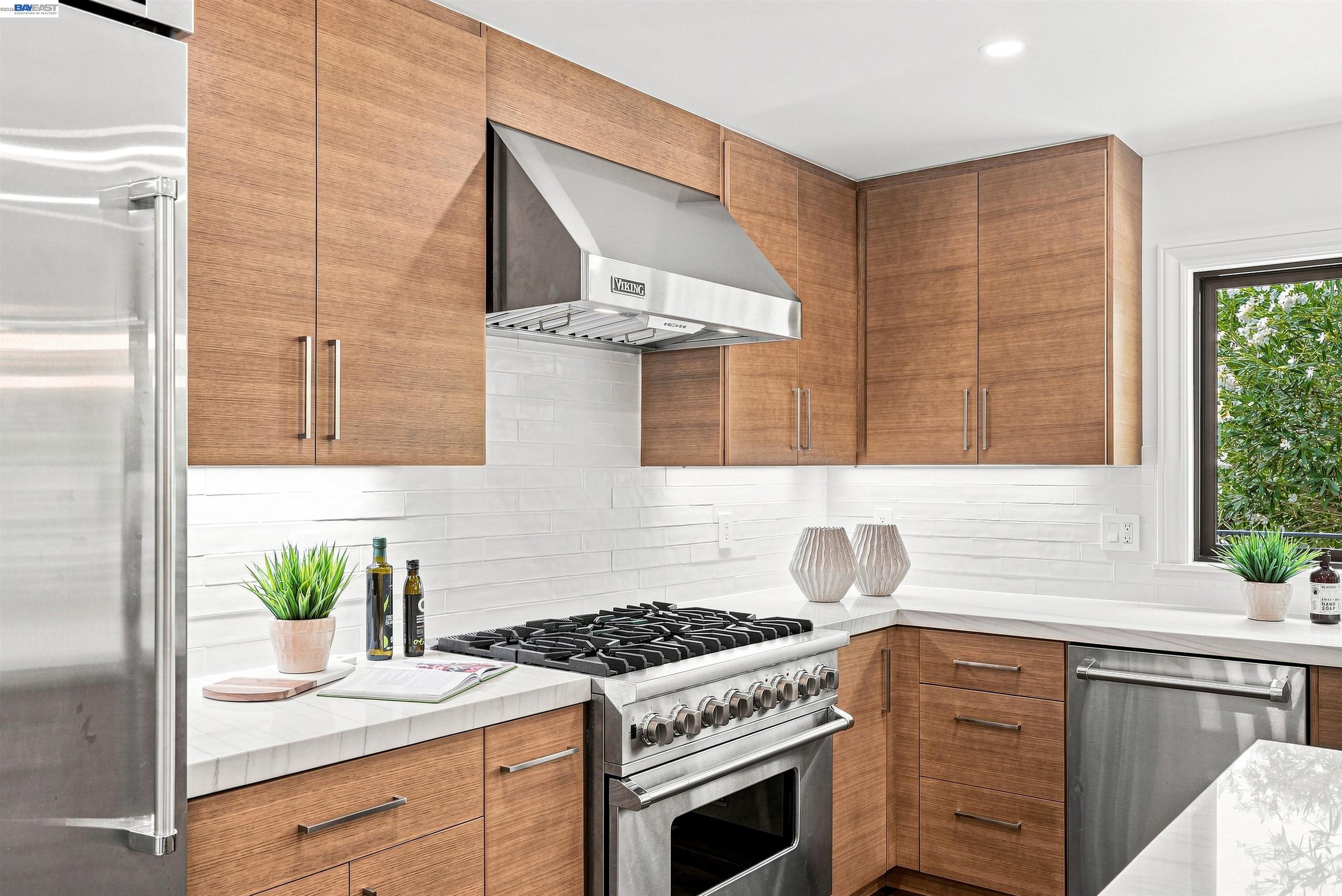 Modern kitchen with warm wood cabinets, white counters, and a stainless-steel Viking range.