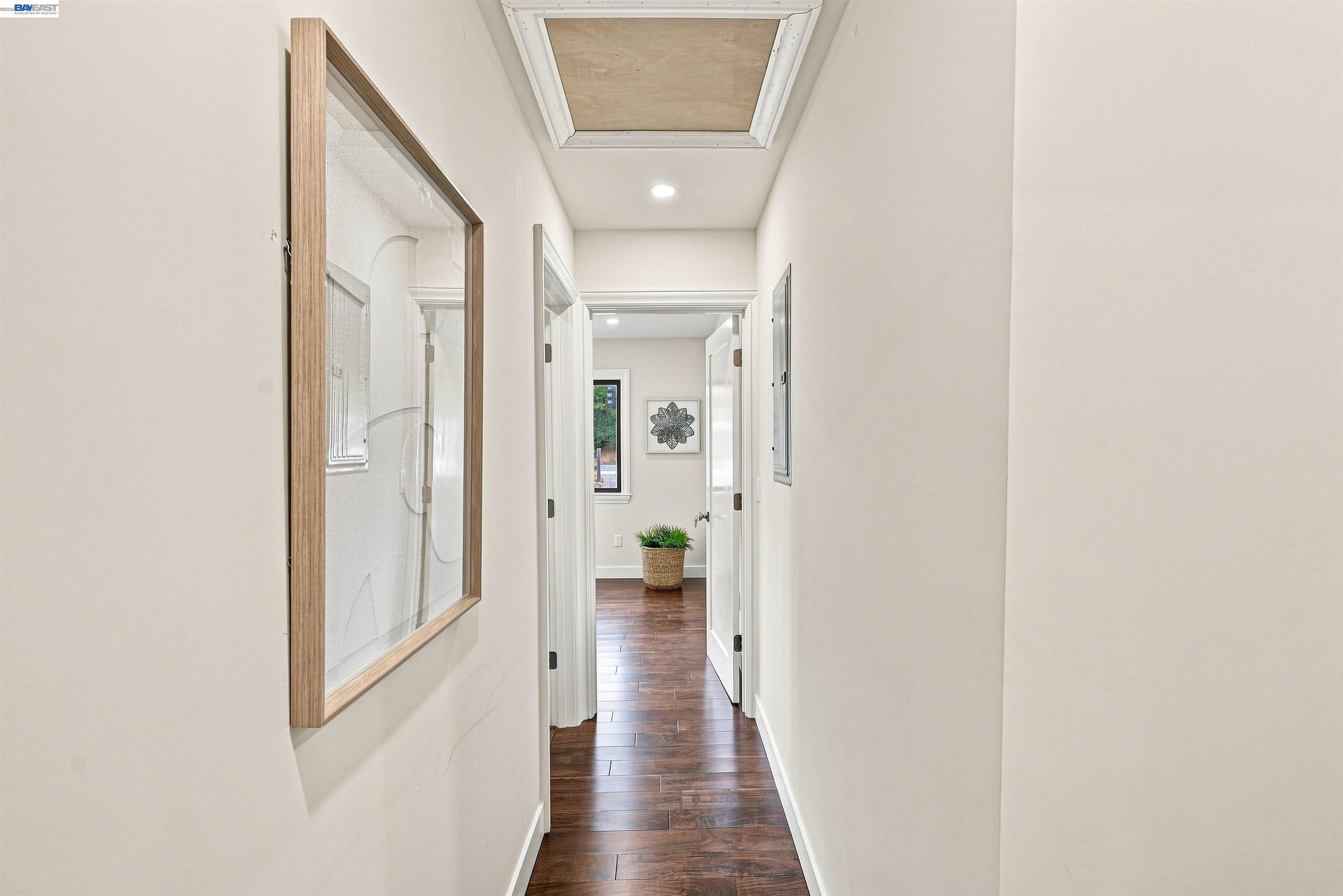 Bright hallway with dark wood floors, a skylight, and framed artwork.