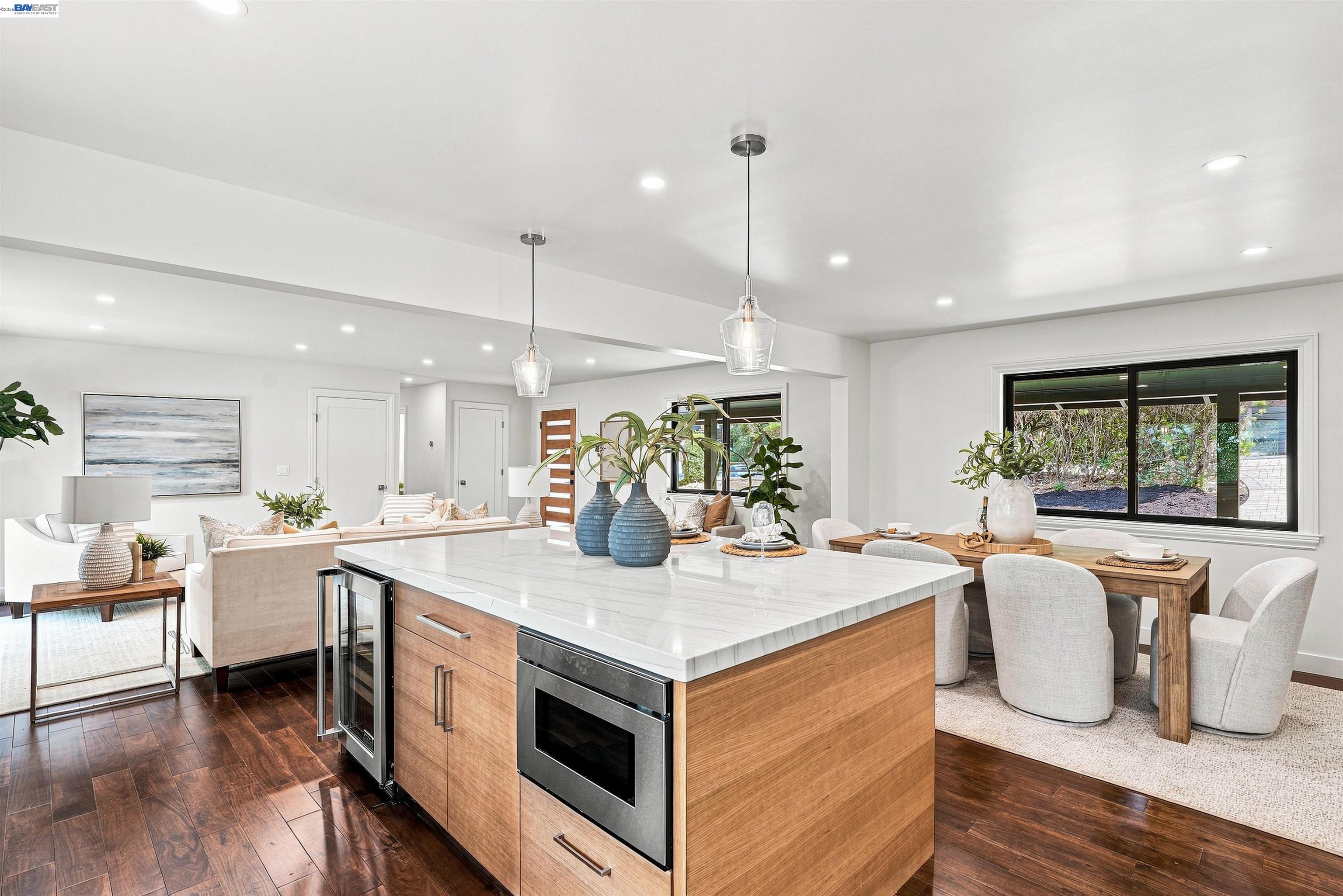 Open-plan kitchen with a large stone island, wood cabinetry, and an adjoining dining and living area.