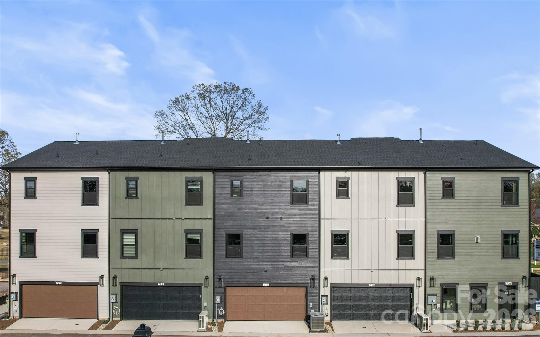 Row of attached townhomes with varied siding and individual garages.