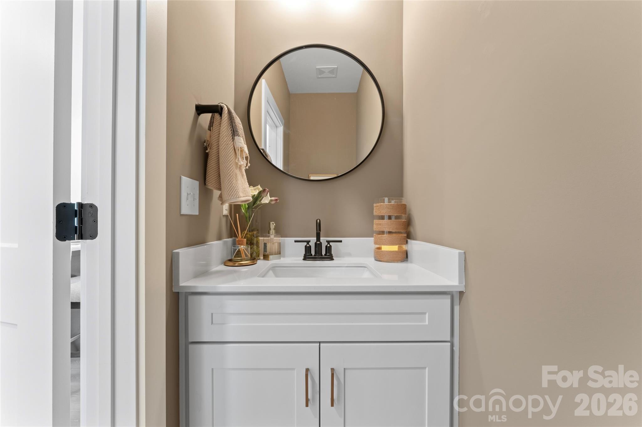 Bathroom vanity with a white sink, black faucet, and round mirror above the counter.