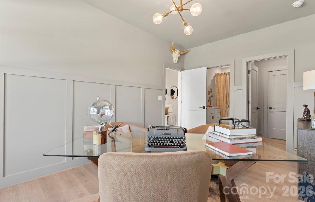 Furnished home office with a glass desk, vintage typewriter, and gray paneled walls.