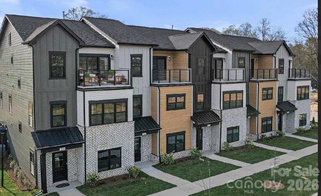 Attached townhomes with contrasting siding, white brick, and upper-level balconies.