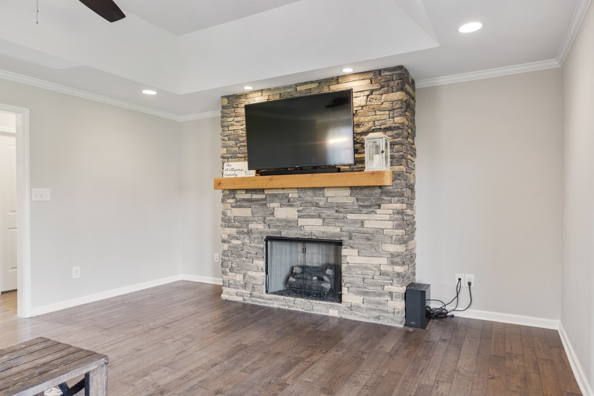 Living room with a stone fireplace and mounted television above a wood mantel.