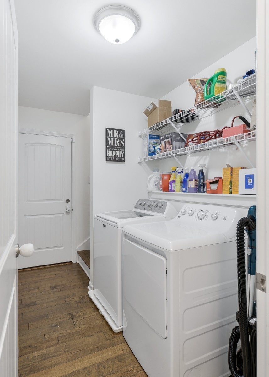 Laundry room with white washer and dryer beneath stocked wire shelves.