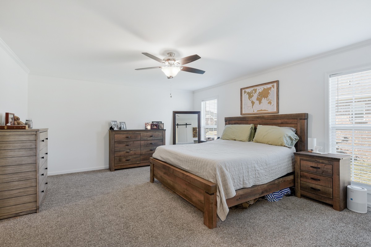 Furnished bedroom with a wooden bed, matching dressers, and a framed world map above the headboard.