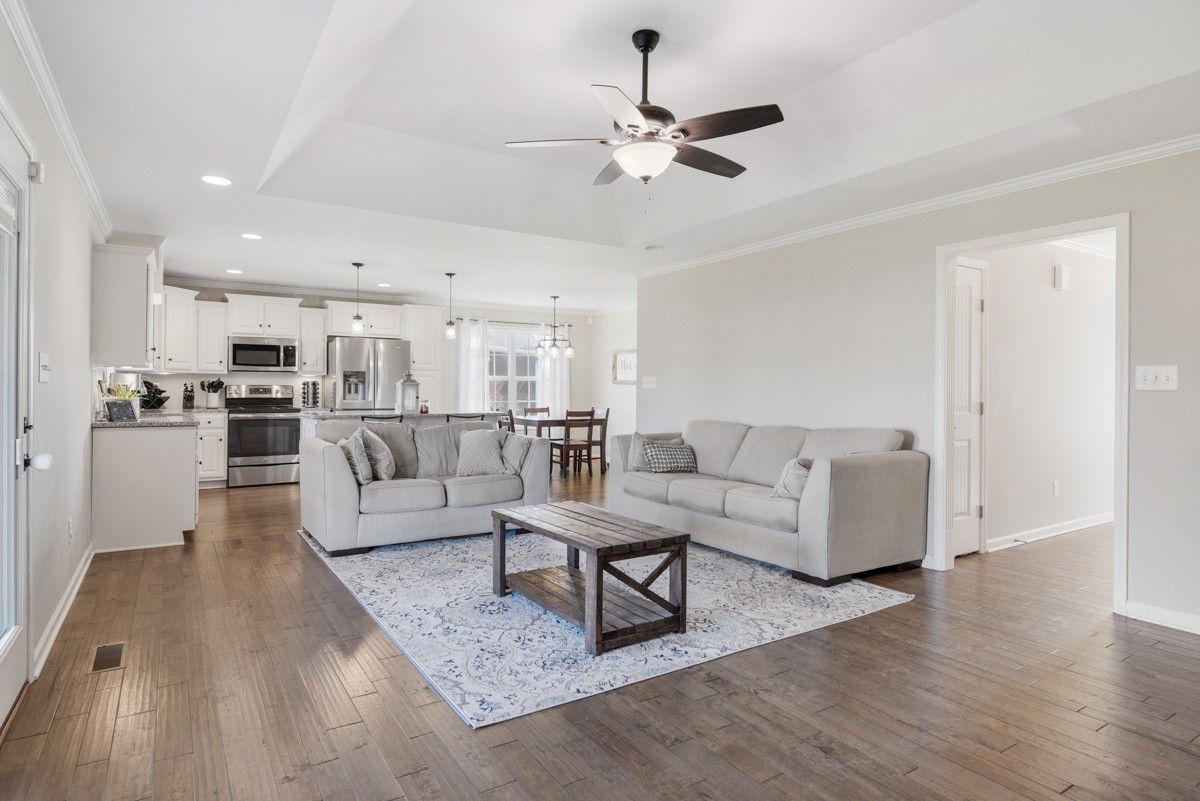 Open living room with two gray sofas and a wood coffee table beside a white kitchen.