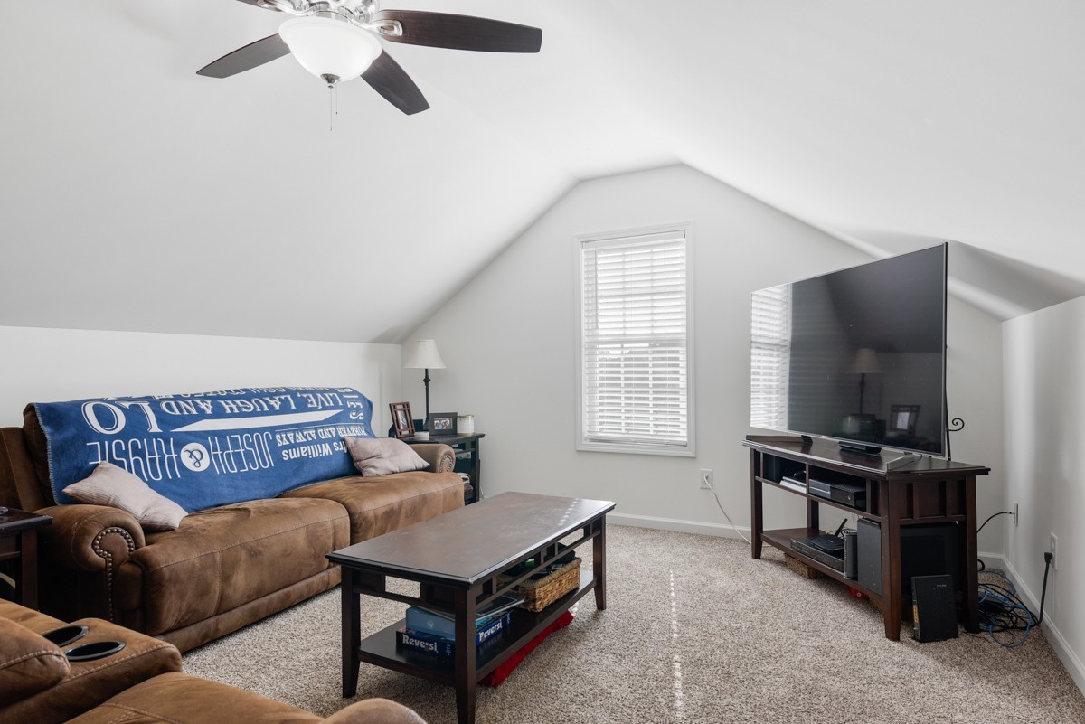 Furnished living room with leather sofas, a large television, and a vaulted ceiling.