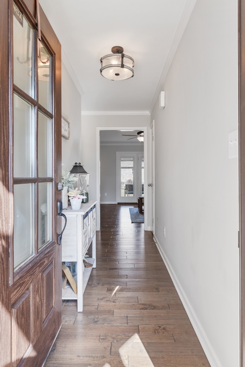 Entry hallway with a glass-paneled wood front door, plank flooring, and a console table.