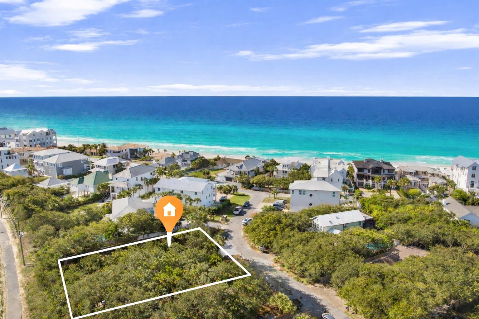 Aerial view of a vacant coastal lot outlined near the turquoise ocean.