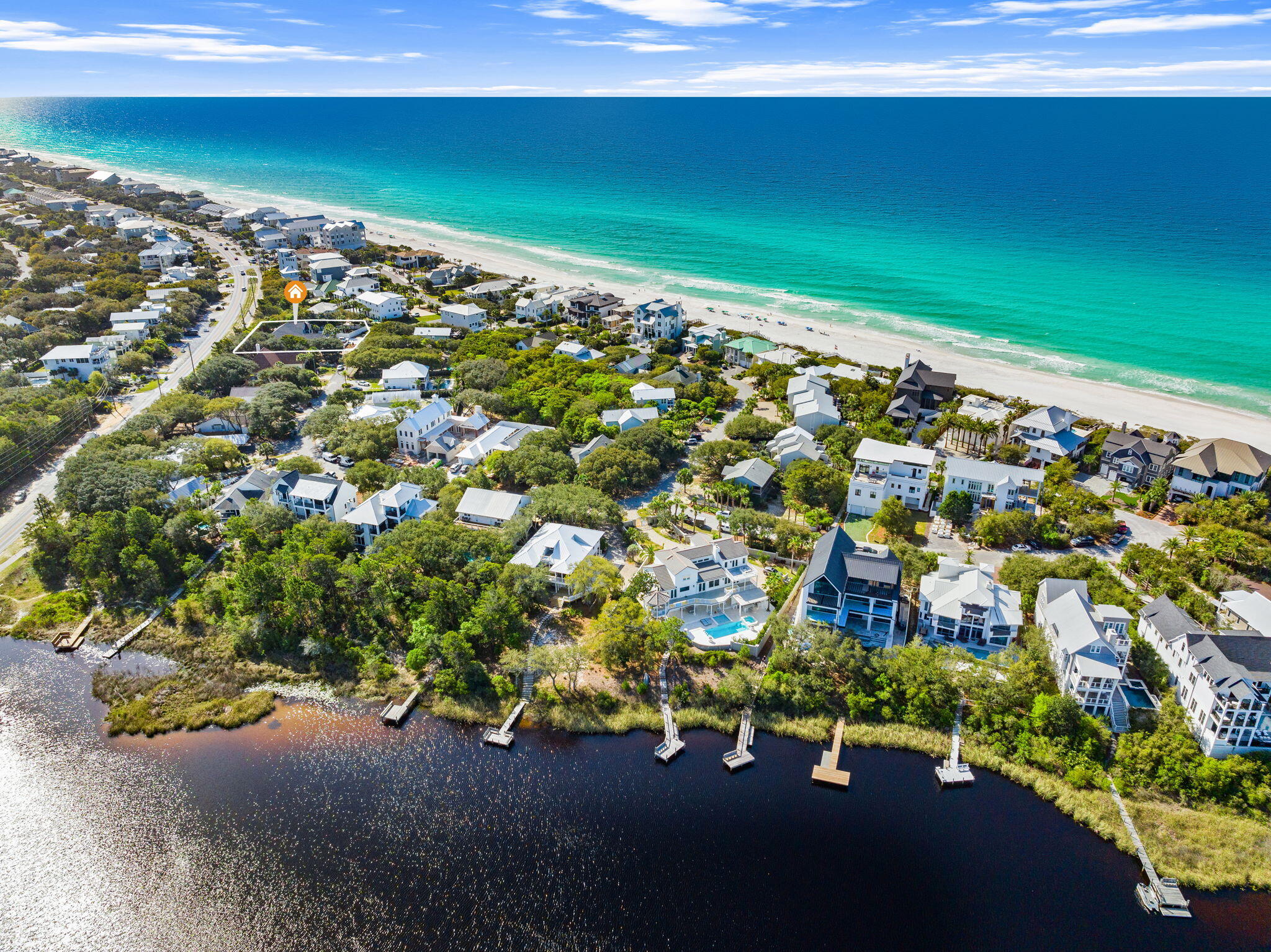 Outlined wooded lot between the Gulf beach and bay, surrounded by coastal homes.